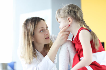Pediatrician doctor examines little girl throat closeupの写真素材