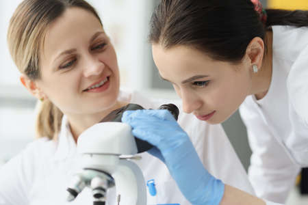 Female scientists chemists looking through microscope in laboratoryの写真素材