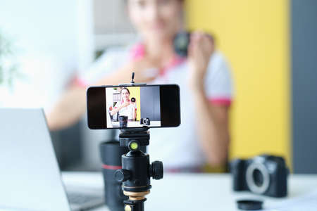Woman smiling at camera while recording lens review for followersの写真素材