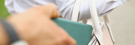A man steals a wallet from a womans bag close upの写真素材