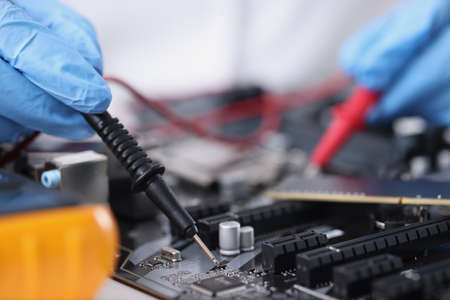 Master in gloves with equipment is testing computer motherboardの写真素材