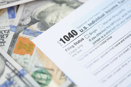 Individuals tax return form 1040 and dollars are on tableの写真素材