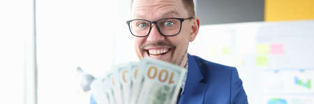 Joyful businessman holds cash in his handsの写真素材