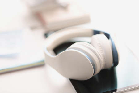 Headphones and tablet are on table. Listening apps and learning foreign languagesの写真素材