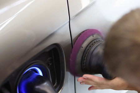 Master repairman polishing car body using machine closeup