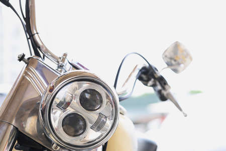 Round motorcycle headlight with handlebars and mirrors closeup