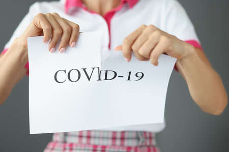 Woman tears up paper that says COVID-19の写真素材