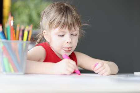 Little girl drawing picture with colored pencils at homeの写真素材