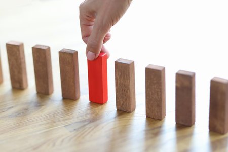 Man hand choosing red block among wooden closeupの写真素材