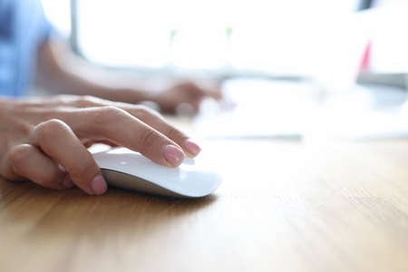 Female hand holding computer mouse and typing on computer keyboard closeup