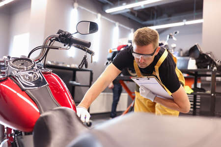 Male locksmith diagnoses a motorcycle at service center closeupの写真素材