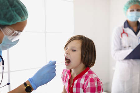 Woman doctor examines the throat of a little girl