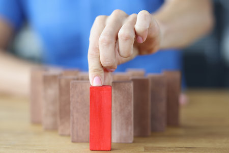 Woman chooses red wooden block among others on wooden table closeupの写真素材