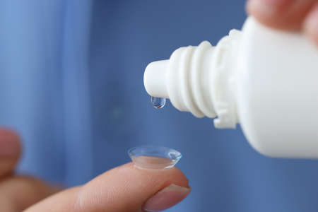 Woman drips liquid into contact lens for eyes closeupの写真素材