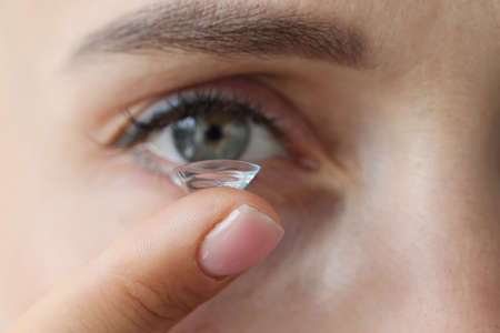 Young woman putting on contact lenses closeupの写真素材