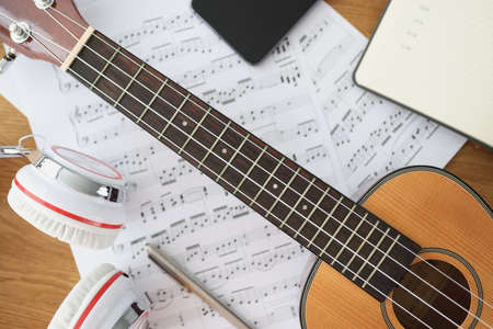 Wooden guitar headphones and music notes on table closeupの写真素材