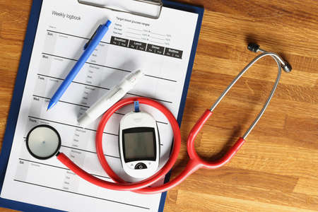 Glucometer with stethoscope lying on glucose control document closeupの写真素材