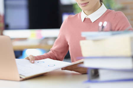 Woman holding folders with documents at table closeup