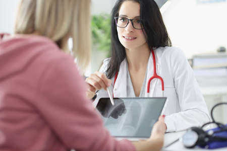 Doctor shows woman patient an X-ray of lungs on tablet closeupの写真素材