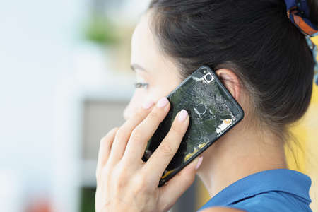 Woman talking on broken cell phone closeup