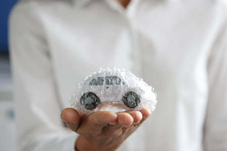 Female agent is holding toy car packed in bubble plastic bagの写真素材
