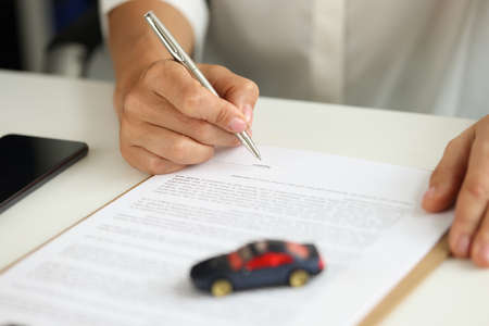Woman signs contract for purchase of car on credit closeupの写真素材