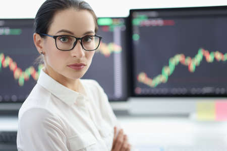 Portrait of businesswoman with glasses on background of electronic stock market analytics closeupの写真素材