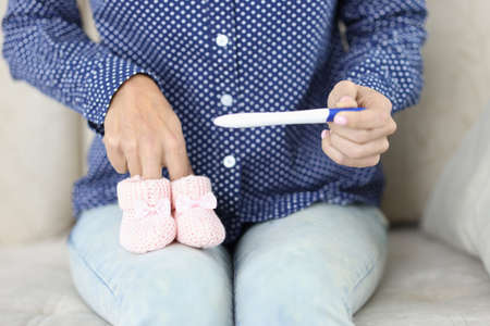 In women hands pregnancy test and small children slippersの写真素材