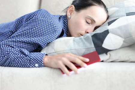 Young woman in depression lies on couch with mobile phoneの写真素材