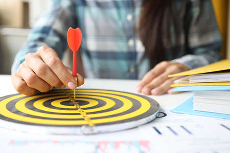 Businesswoman puts dart in center of darts at workplace in officeの写真素材