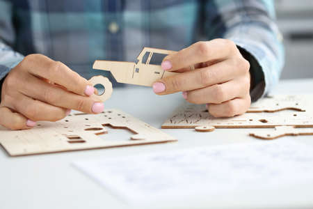 Female hands assemble wooden toy car from different parts