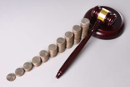 Wooden judge gavel and stacks of coins on tableの写真素材