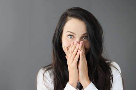 Portrait of smiling young woman covering nose with hand