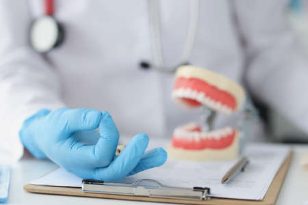 Dentist hand gesture ok on background of artificial jaw