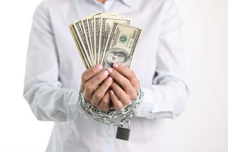 Women hands tied with chain hold one hundred dollar bills