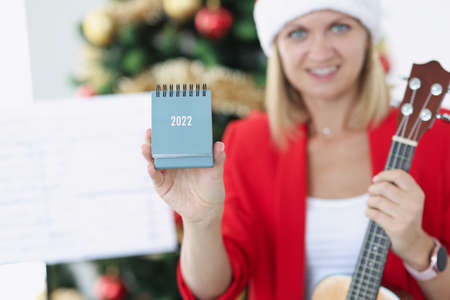 Woman musician holding new year calendar for 2022 near Christmas tree closeupの写真素材