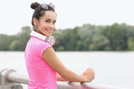 Young smiling woman with headphones on her neck standing on bridgeの写真素材