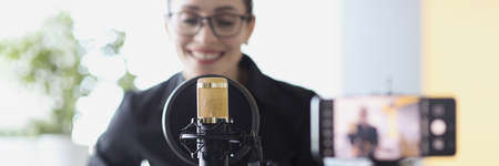 Woman plays guitar and sings while recording a video on smartphoneの写真素材