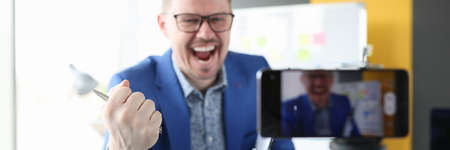 Male blogger emotionally tells interesting successful content on cameraの写真素材