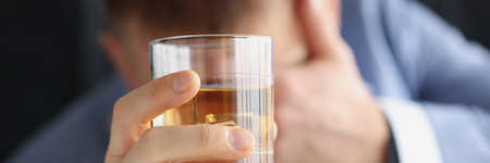 Drunk sad man holds glass with alcoholの写真素材