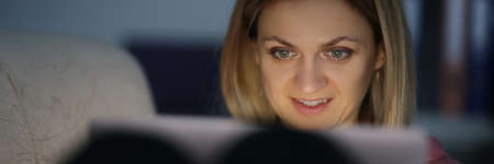 Portrait of woman in dark looks at screen of tablet