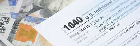 Individuals tax return form 1040 and dollars are on tableの写真素材