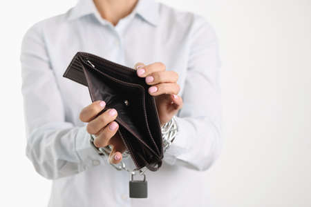 Woman holding empty purse hands tied with chainの写真素材
