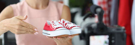 Woman salesman consultant shows to camera red sports shoesの写真素材