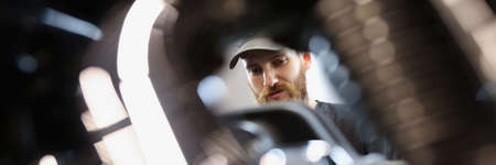 Bearded master locksmith looks at motorcycle engine closeupの写真素材