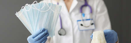Doctor holds medical protective masks and gloves in handsの写真素材