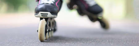 Child riding black rollerblades on road closeupの写真素材