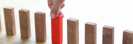 Man hand choosing red block among wooden closeup