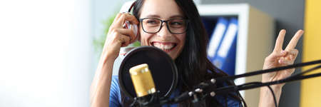 young radio presenter works in studio, she smiles and broadcasts announcements closeupの写真素材