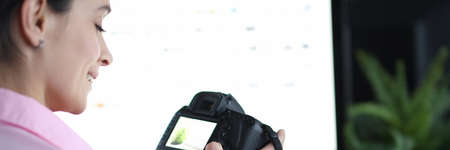 Woman holds camera and presses buttons at workplace closeup